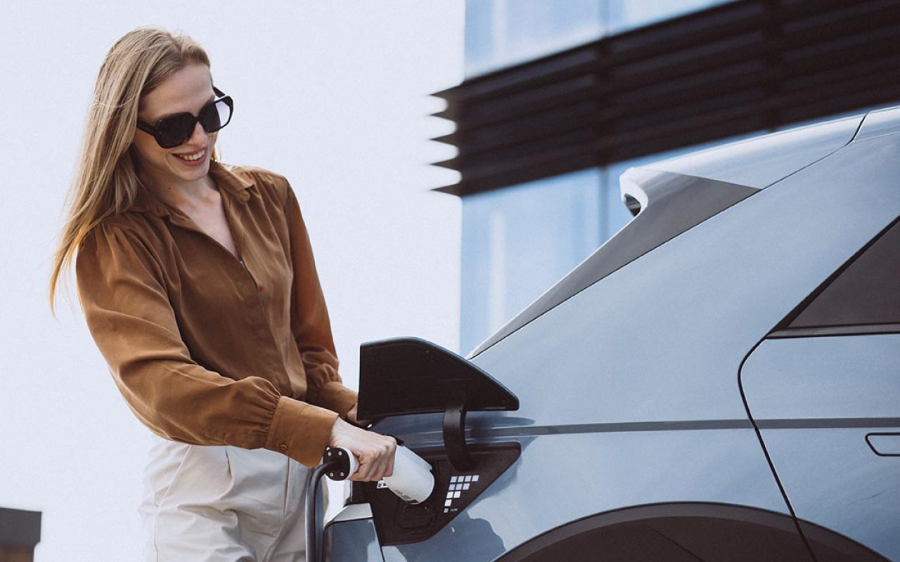 Woman puts charging cable into electric car